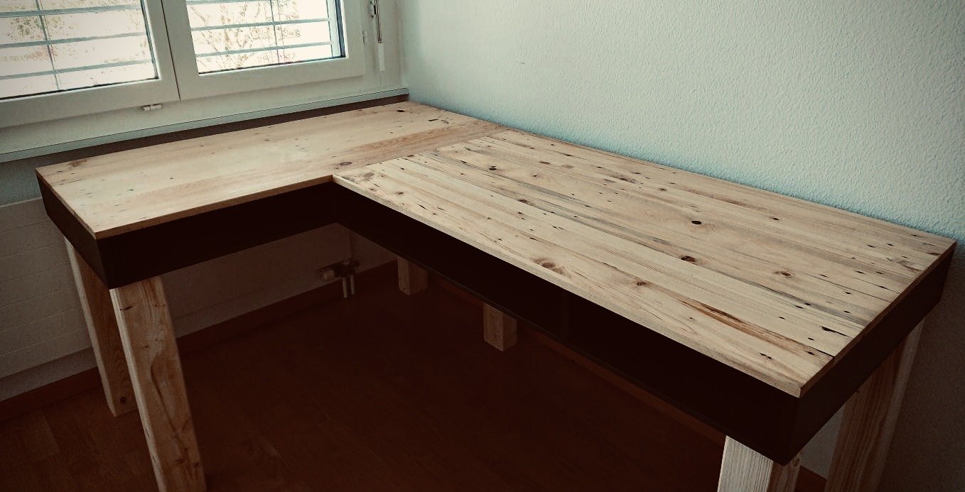 L-shaped desk with a reclaimed pine top and black apron, under a window