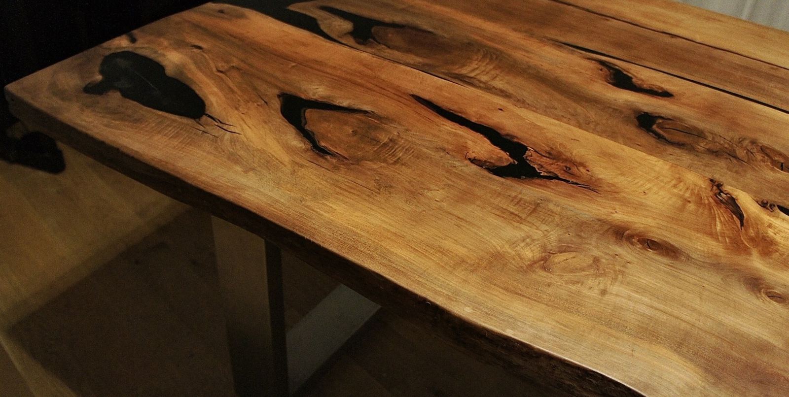 Close view of the walnut dining table top with black-filled voids